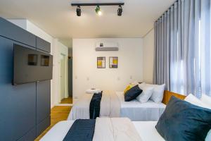 a bedroom with two beds and a flat screen tv at Studio com 2 Camas de Casal e Garagem - EIX0705 in Curitiba