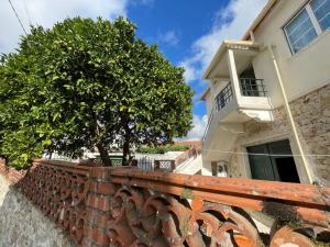 una pared de ladrillo con un árbol delante de un edificio en Orange Tree house, Silver Coast, Alcobaça, Nazaré, en Alpedriz
