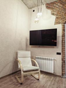 第比利斯Old Tbilisi style Apartment的房间里有一把白色椅子，墙上有一台电视 更多11张照片