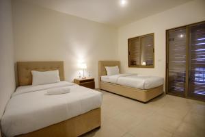 a bedroom with two beds and a night stand with two lamps at منتجع تالابيه العقبة in Aqaba