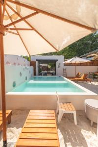 a pool with a table and a chair and an umbrella at Villas Manglar Sisal 3 by WoWay Experiences in Sisal