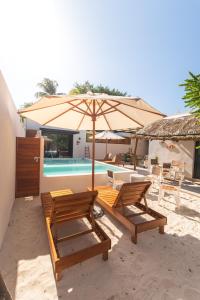 a couple of chairs and an umbrella next to a pool at Villas Manglar Sisal 3 by WoWay Experiences in Sisal +11 photos