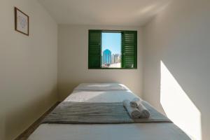 a bed in a white room with a window at Central, Barato e Espaçoso in Maringá