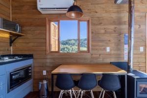 a kitchen with a table with stools and a window at Cabana c/ vista panorâmica e jacuzzi - VST026 in São Paulo dos Pinhais
