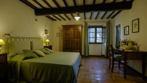 Un dormitorio con una cama y un escritorio y una ventana. en Villa Storica Volterra, en Volterra