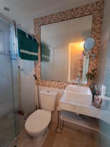 a bathroom with a toilet and a sink and a mirror at Pousada Odoyá Beach - Casal in Conde