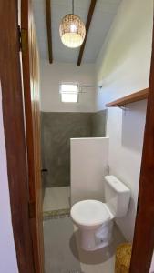 a bathroom with a toilet and a chandelier at Kitnets ESPELHO a 160 metros da Praia do Espelho in Praia do Espelho +18 photos