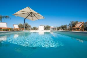 a swimming pool with an umbrella and two chairs at Villa Corbezzolo in Galatone