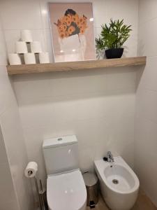 a white bathroom with a toilet and a sink at Solsuites in Almería