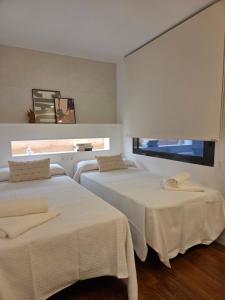 a room with two beds with white sheets and a window at Solsuites in Almería