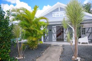 een wit huis met palmbomen ervoor bij La Petite Villa Guadeloupe in Sainte-Anne