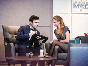 a man and a woman sitting in chairs with a table at Mercure Budapest City Center in Budapest
