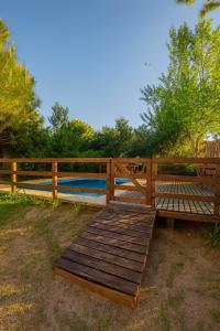 eine Holzterrasse mit einer Bank neben einem Zaun in der Unterkunft Latitud 44 in Mar Azul