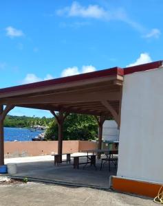 a picnic shelter with a picnic table and water at Maison exurville in Le Robert