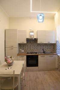 une cuisine avec des armoires blanches et une table avec des chaises dans l'établissement Domus Marina - Ionio room, à Mondragone