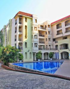 a hotel with a swimming pool in front of a building at Luxury Pool view Apartment w Jacuzzi by Mirabella in Mapusa +16 photos