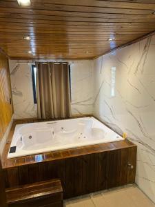 a large bath tub in a bathroom with marble walls at Cabana Raízes - LaCabanasEco in Chapecó