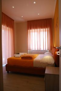 a bedroom with a large bed with orange curtains at Domus Marina - Egeo Apartment in Mondragone