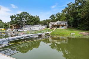 ein Haus mit einer Brücke über ein Gewässer in der Unterkunft Gentle Sloped Lot, Private Dock, Boat Slip, Kayaks, Fire Table, Lakeview Deck, Family Friendly in Purvis