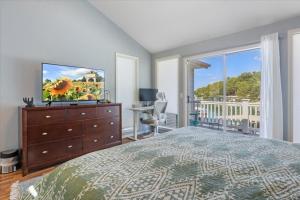 Un dormitorio con una cama y un televisor y un balcón. en Amazing Wall of Windows, Swim Dock & Pet Friendly, en Arrowhead Beach