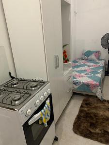 een keuken met een fornuis en een slaapkamer met een bed bij Kitnet Dream House 3 in Bayeux