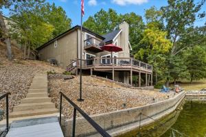 een huis aan de oever van een rivier met een vlag bij Expansive Deck, Beautiful Views, Private Dock & Boat Slip in Sunrise Beach