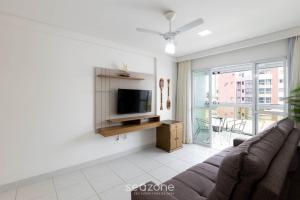 Una sala de estar con un sofá y un televisor. en Apto c/ balcón y vista al mar en Guarapari CMD0311, en Meaípe