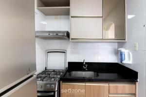 una cocina con fregadero y estufa en Apto c/ balcón y vista al mar en Guarapari CMD0311, en Meaípe