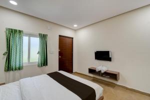 Un dormitorio con una cama y un televisor de pantalla plana. en Hotel O EVA, en Gundipet