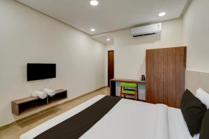 Una habitación de hotel con una cama y un televisor. en Hotel O EVA, en Gundipet