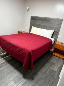 1 dormitorio con cama roja y suelo de madera en Vegas motel, en West Athens