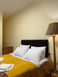 a large bed with white pillows and a lamp at Hotel Wintera Gudauri in Gudauri