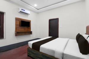 a bedroom with a bed and a tv on the wall at Hotel O Smriti Villa in Ballygunge