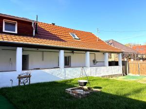 a white house with an orange roof and a yard at Míra Apartman in Gödöllő