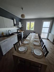 une longue table dans une cuisine avec des assiettes et des verres dessus dans l'établissement Le Domaine du Bien-Être, à Rahon