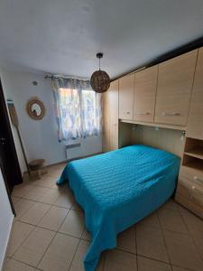 une chambre avec un lit avec une couverture bleue dans l'établissement Chez Valérie et Stéphane, Les terrasses de Lozari, à Belgodère