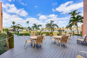 a deck with tables and chairs and palm trees at Waterfront Views and Pool Access Punta Gorda Escape in Burnt Store Marina
