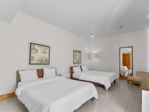 two beds in a room with white walls at Stay at Ultravioleta Cabarete Beachfront Apartments by EvoKey in Cabarete +20 photos