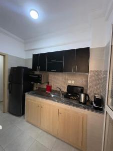 uma cozinha com uma geladeira preta e uma pia em Appartement a 10 min de l aeroport de marrakech em Marraquexe