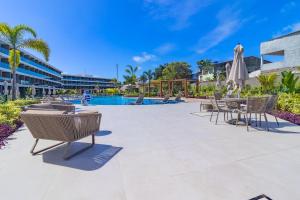 a patio with chairs and a table and a pool at Beach Class Summer resort condominium by Carpediem in Porto De Galinhas