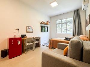 a living room with a couch and a bed and a desk at Estúdio na melhor rua do Leblon in Rio de Janeiro