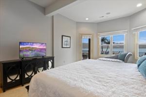 a bedroom with a large bed and a flat screen tv at Luxury Lakefront Escape w/ Heated Pool, Hot Tub & Theater in Sunrise Beach +76 photos