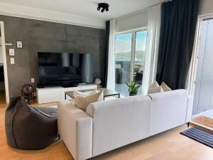 a living room with a white couch and a flat screen tv at Large luxurious apartment with private terrace and parking in Bergen