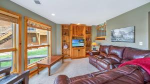 a living room with a leather couch and a television at Hot Tub, Fire Pit, Awesome Loft & Amazing Views! in Buck Creek