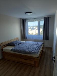 Un dormitorio con una cama con edredón azul y una ventana. en 3-izbový byt, en Prievidza