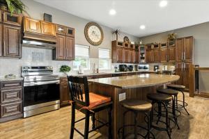 een keuken met houten kasten en een groot eiland met barkrukken bij Lakefront Home w/ Double Deck, Slip, Firepit & Game Room in Sunrise Beach