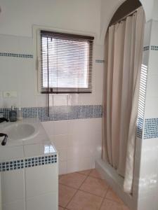 a white bathroom with a sink and a window at La Maison De Stephanie in Porto-Vecchio