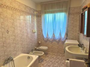 a bathroom with a toilet and a tub and a sink at Appartamento La Coccinella in Gonàrs