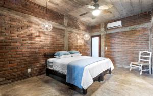 プンタ・ミタにあるSummer Salt Beach Casitaのレンガ壁のベッドルーム(ベッド1台、椅子付)