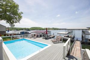 ein Pool auf einem Deck neben einem Wasserkörper in der Unterkunft Private Lakefront Pool, Amazing Dock Sleeps 26 in Purvis